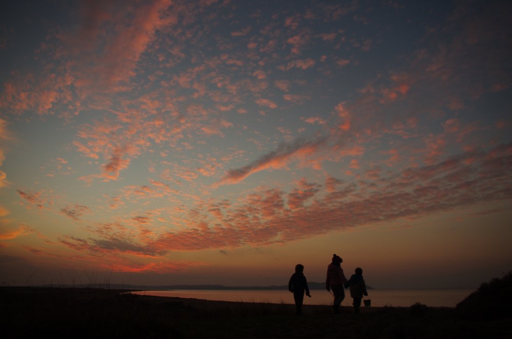 Sonnenuntergang mit rotem Himmel und 3 spielenden Kindern am Strand