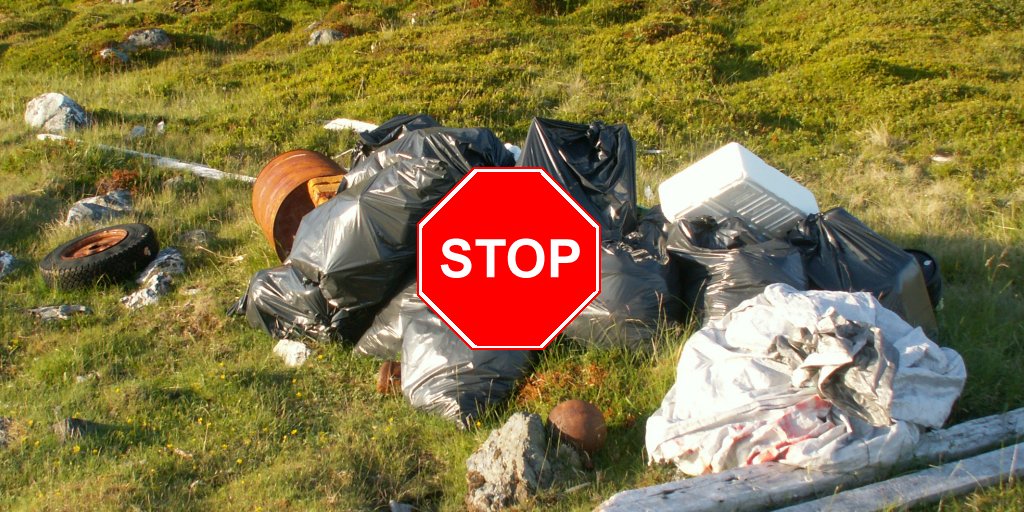 Müllhaufen auf grüner Wiese am Fjord in Nordnorwegen mit rotem Stoppschild