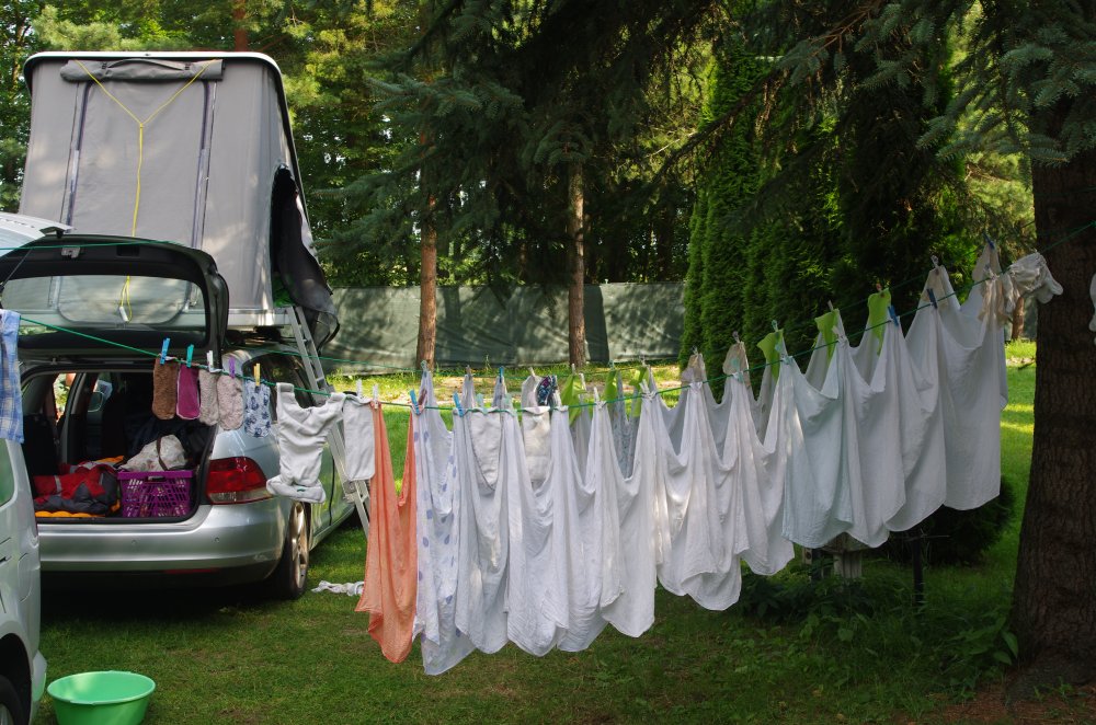 Wäscheleine mit Stoffwindeln zwischen VW Golf mit Dachzelt und einigen Bäumen in Polen